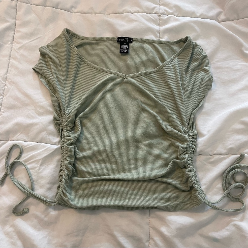 Sage green top with 2 drawstrings on the sides.